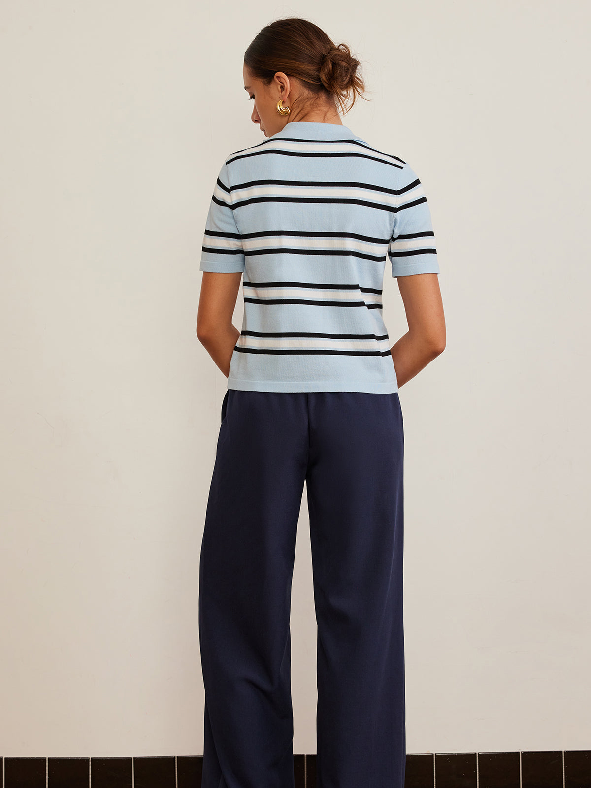Striped knit top with lapel detail in light blue, navy, and white paired with navy wide-leg pants.