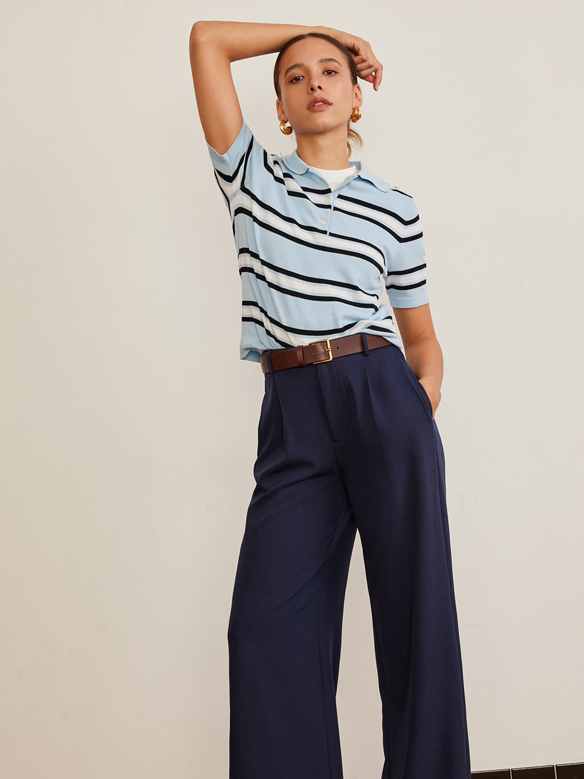 Striped knit top with lapel detail, paired with navy wide-leg trousers and brown belt.