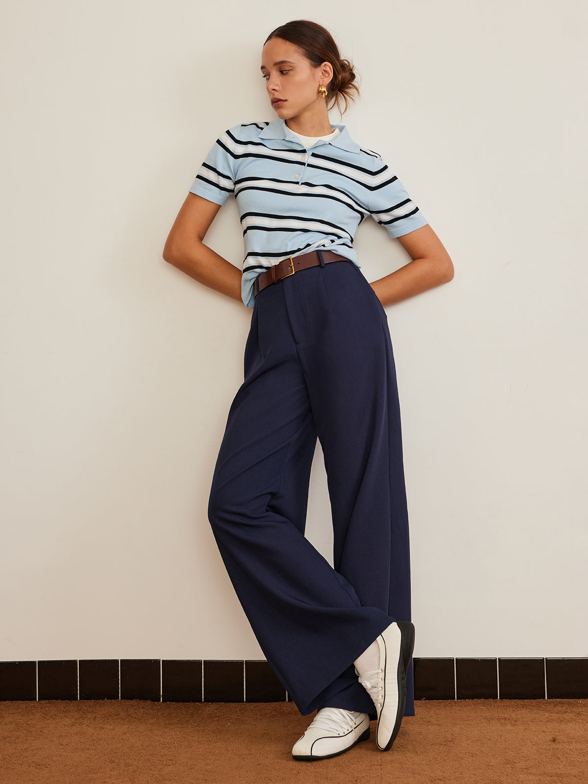Striped knit top with lapel detail, navy high-waisted wide-leg trousers, brown belt, white shoes.
