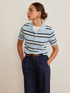 Striped knit top with lapel detail layered over a white shirt and navy high-waisted trousers.