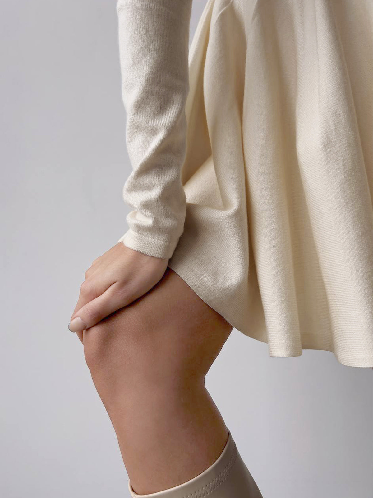 A simple pleated sweater dress with a short hem, featuring soft fabric and subtle pleats.