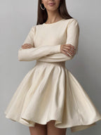 A soft knit mini sweater dress with long sleeves, pleated detail, and a flared skirt.
