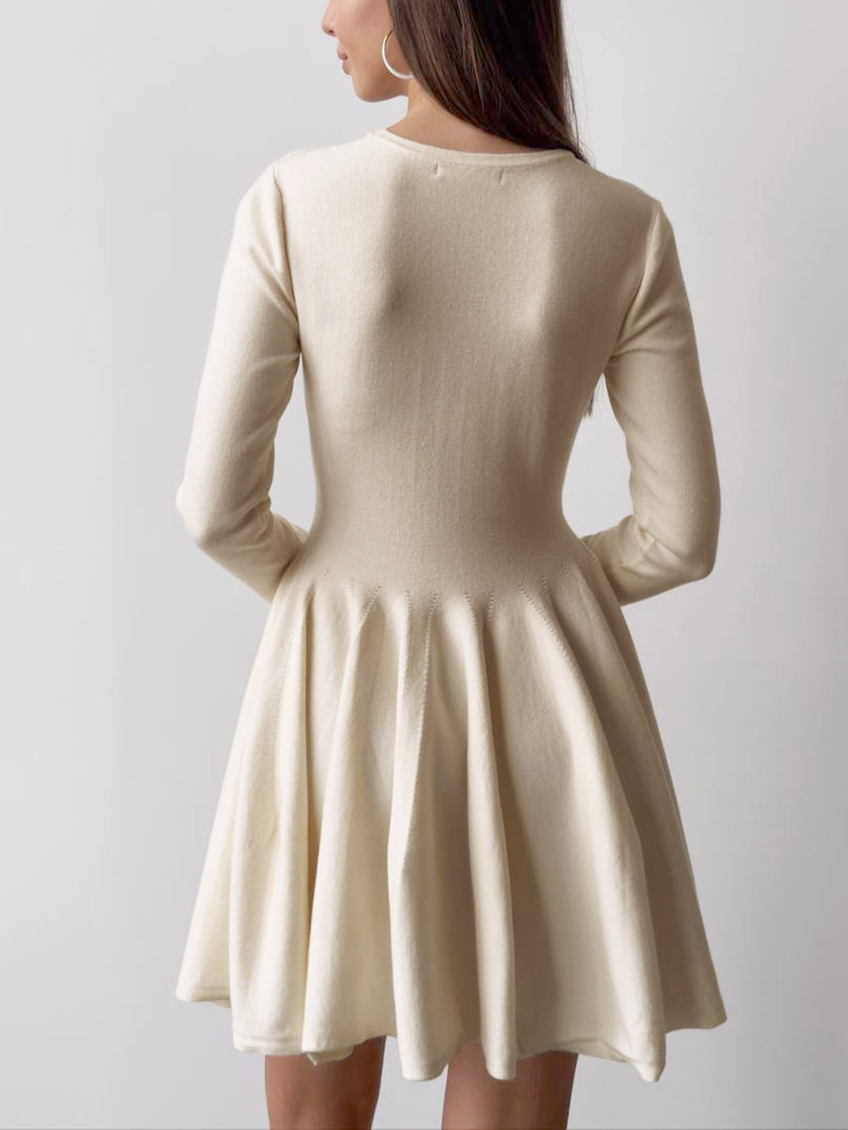 Cream-colored LA FINE FLEUR pleated sweater dress with long sleeves and short hem.