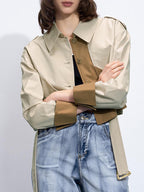 Dual-tone trench coat with buckle belt over a black top and high-waisted blue jeans.