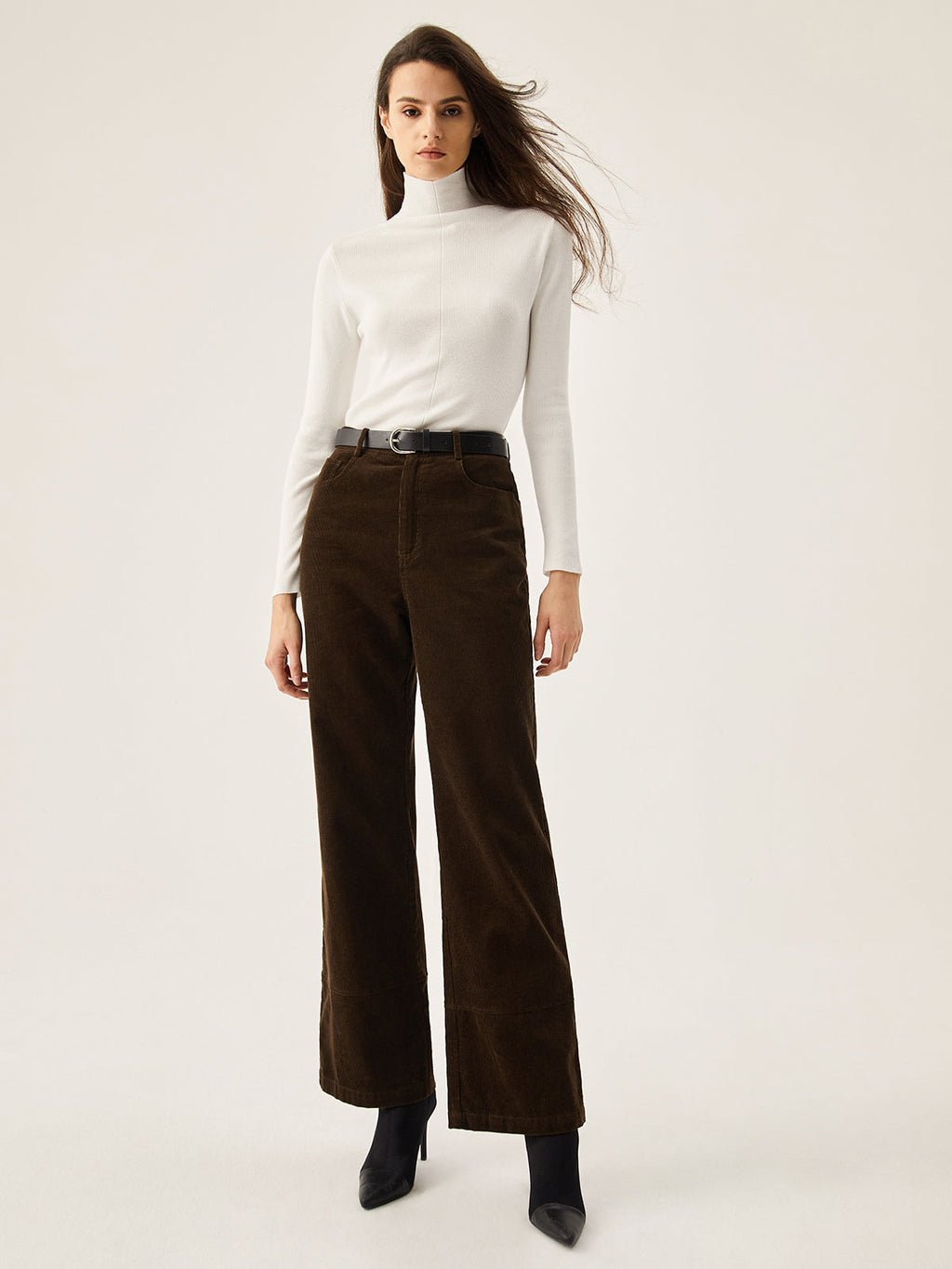 Corduroy wide leg pants with convenient pockets, paired with a white turtleneck and black belt.