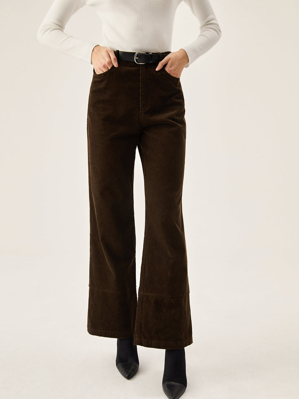 Dark brown corduroy wide leg pants with convenient pockets, styled with a white long-sleeve top.
