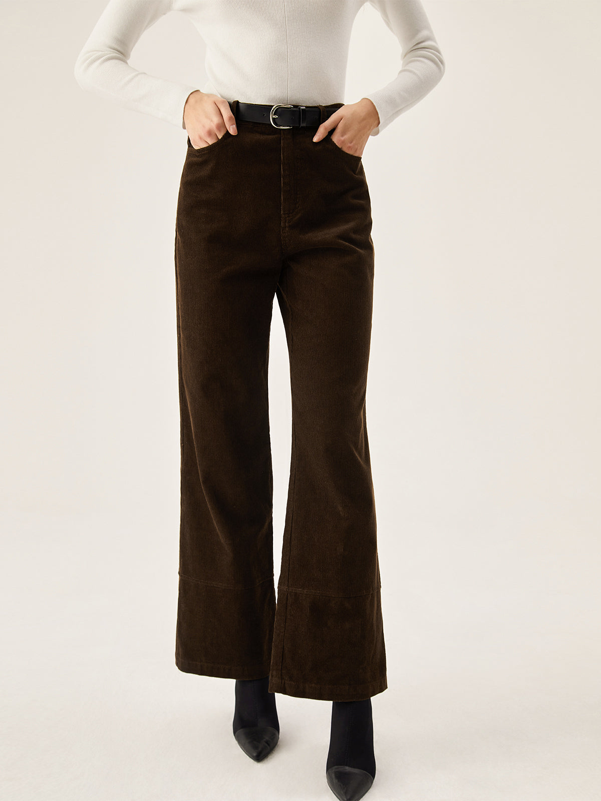 Dark brown corduroy wide leg pants with convenient pockets, styled with a white long-sleeve top.