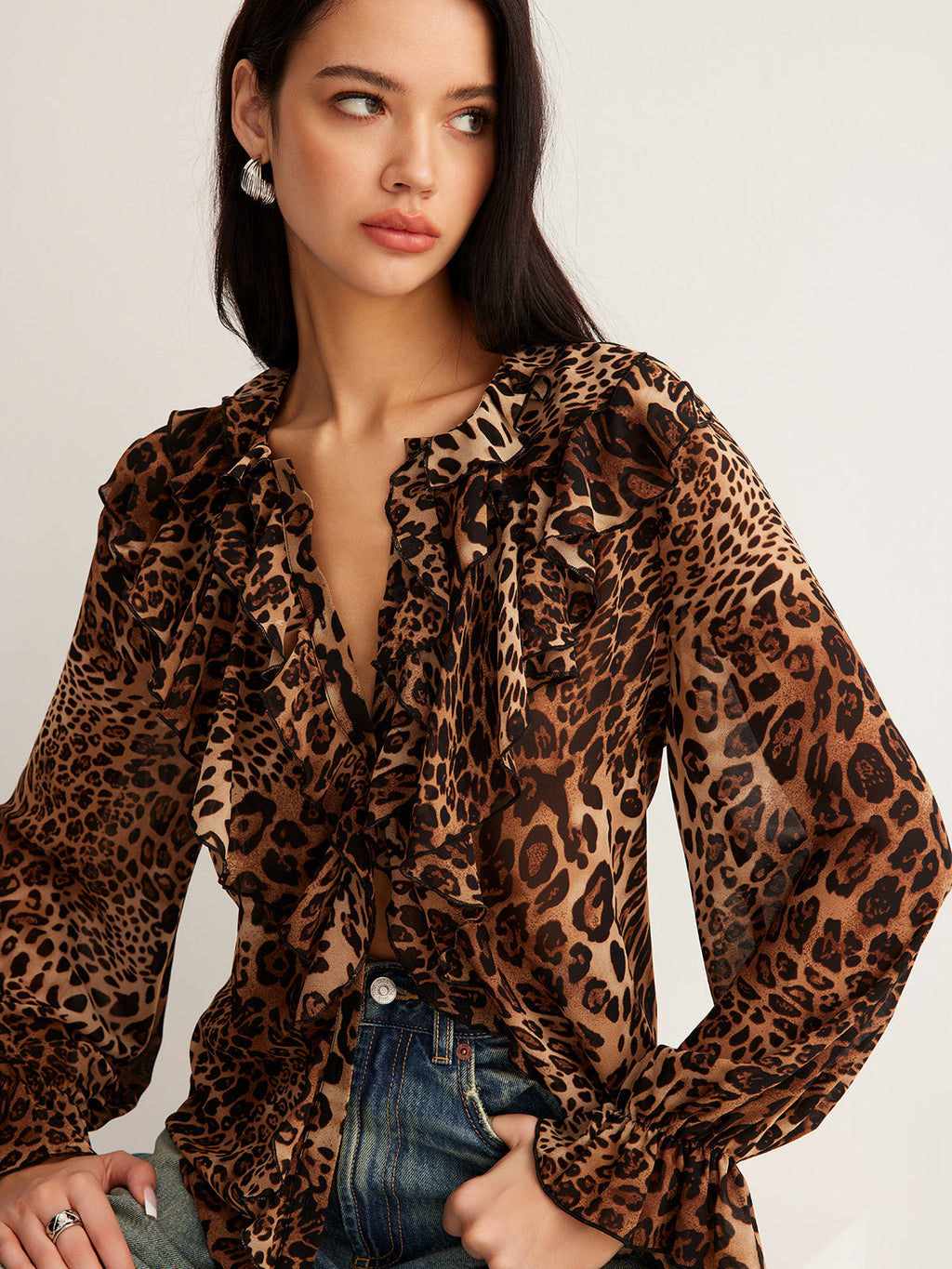 A leopard print blouse with ruffle detail, sheer long sleeves, and classic blue jeans.