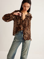 Long-sleeved leopard print blouse with ruffle detail, paired with classic blue jeans.
