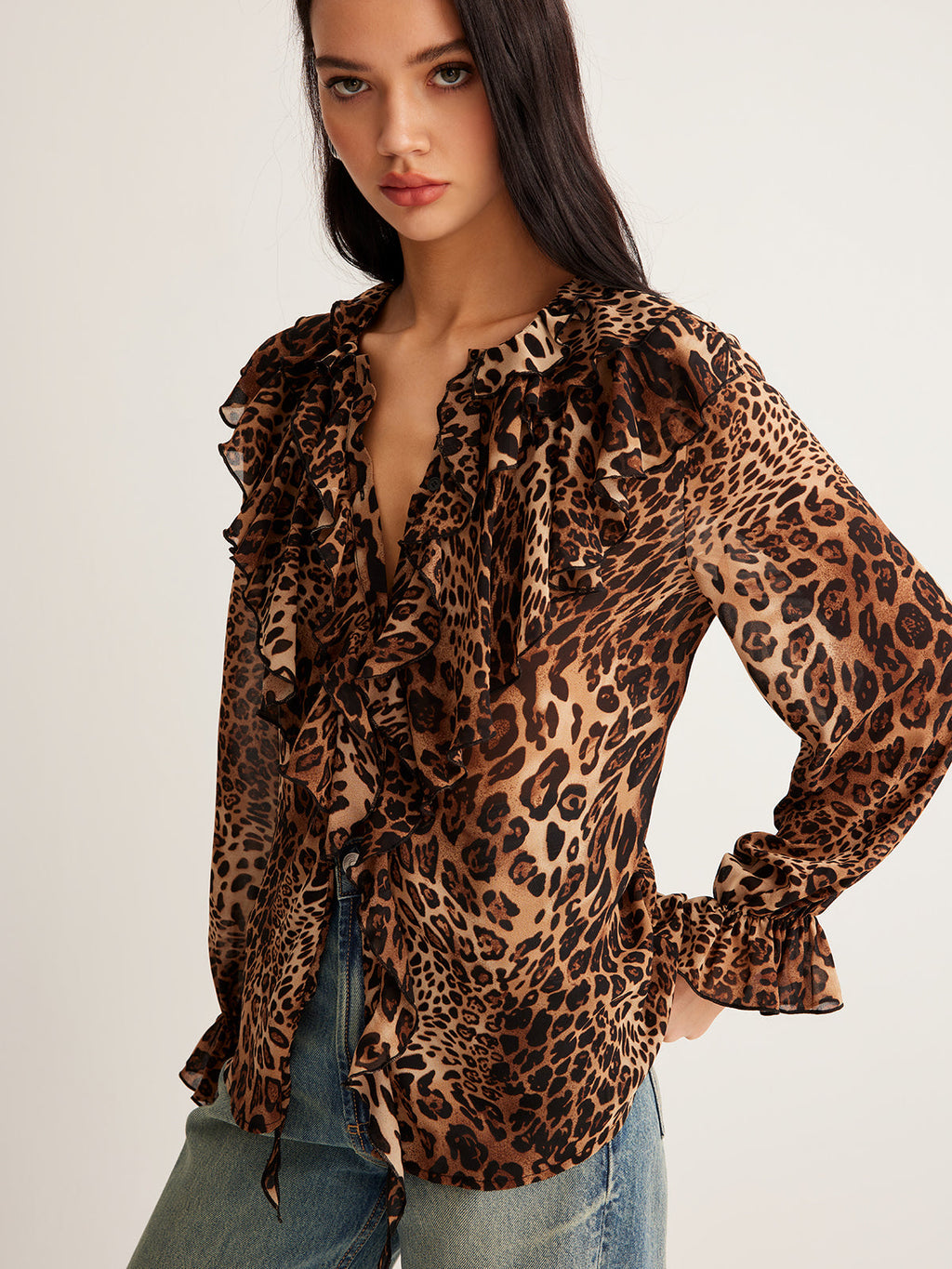 Leopard print blouse with ruffle details, sheer long sleeves, and blue denim jeans.