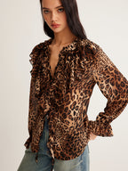 Leopard print blouse with ruffle details, sheer long sleeves, and blue denim jeans.
