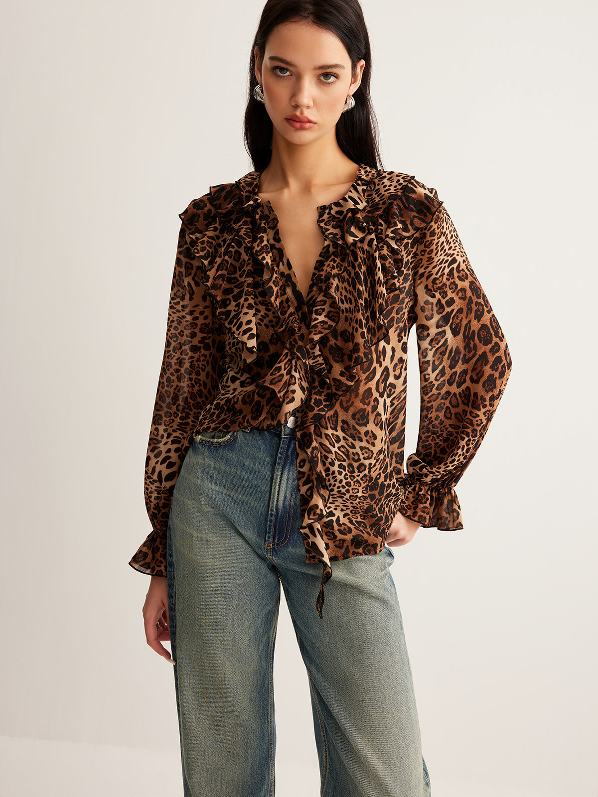 LA FINE FLEUR Leopard Print Blouse with Ruffle Detail paired with high-waisted blue jeans.