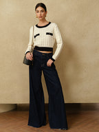 A plaid pullover sweater with contrasting trim and wide-leg dark blue jeans.