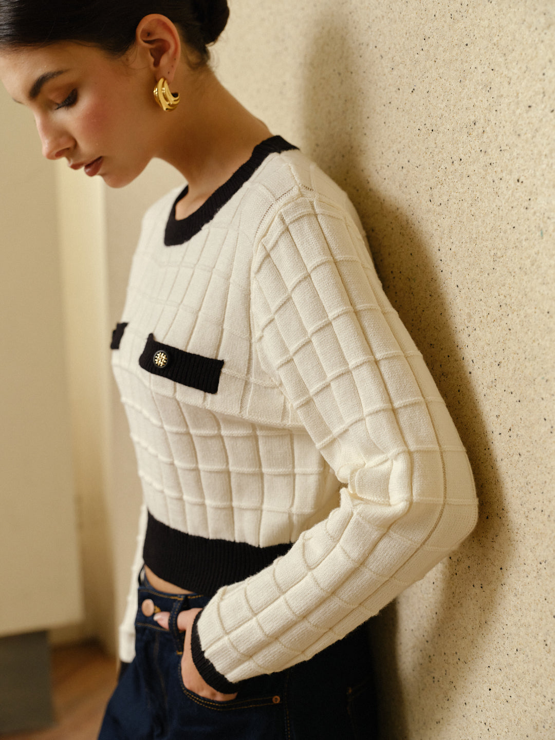 A plaid pullover sweater with contrasting trim, styled with dark high-waisted jeans.