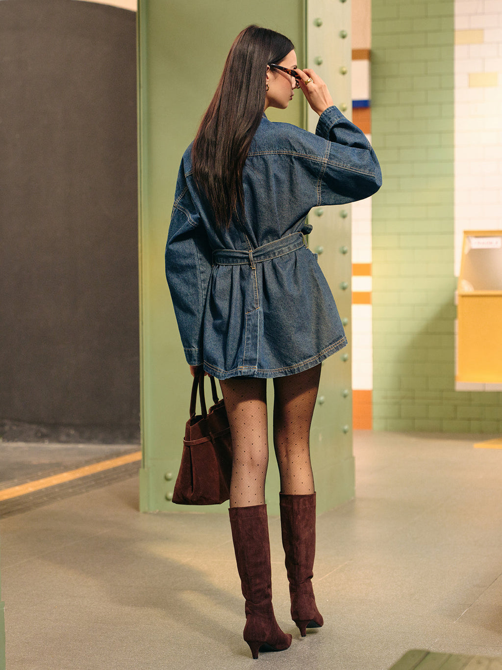 Denim cargo jacket with belted detail, sheer polka-dot tights, and knee-high brown suede boots.