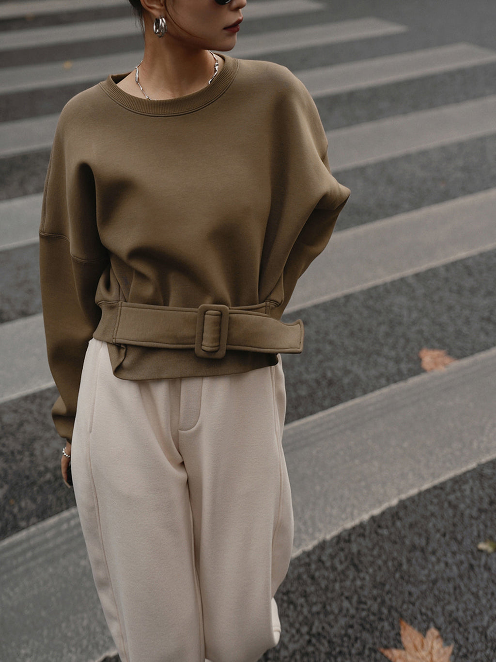 LA FINE FLEUR's Cinched Waist Short-Length Sweatshirt Sweater paired with cream pants.