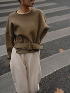 LA FINE FLEUR's Cinched Waist Short-Length Sweatshirt Sweater paired with cream pants.