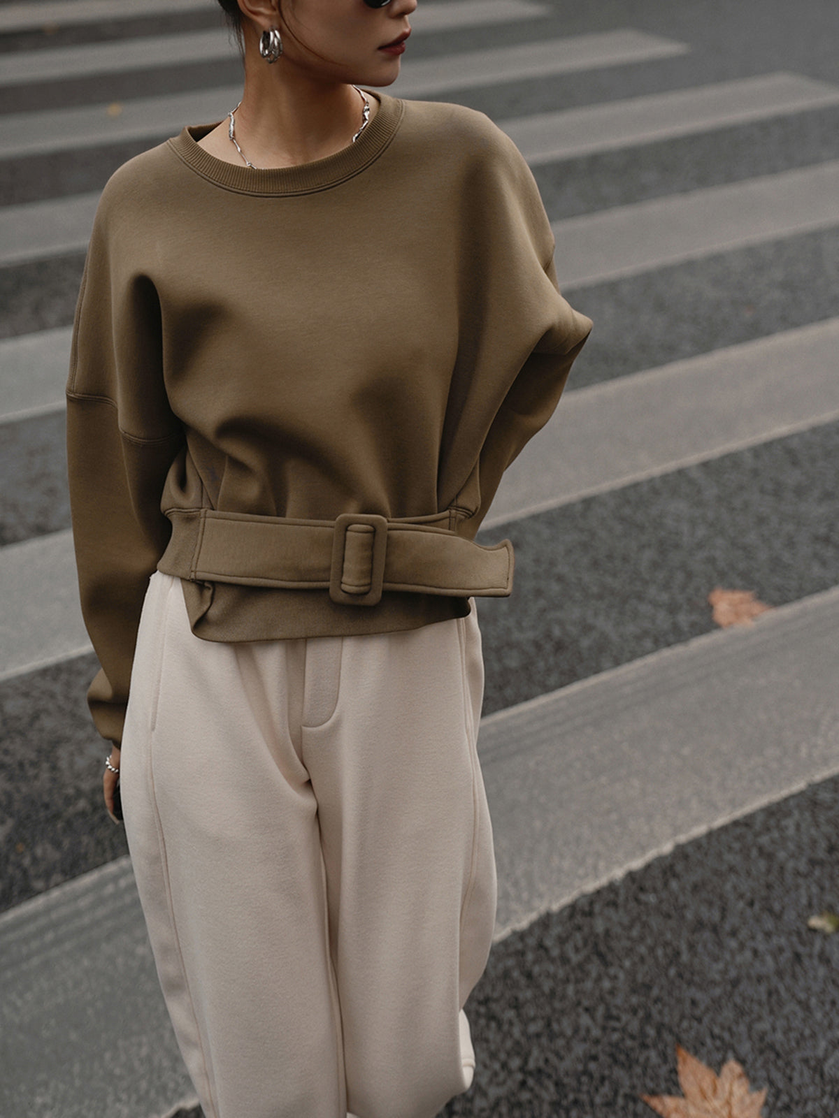 LA FINE FLEUR's Cinched Waist Short-Length Sweatshirt Sweater paired with cream pants.