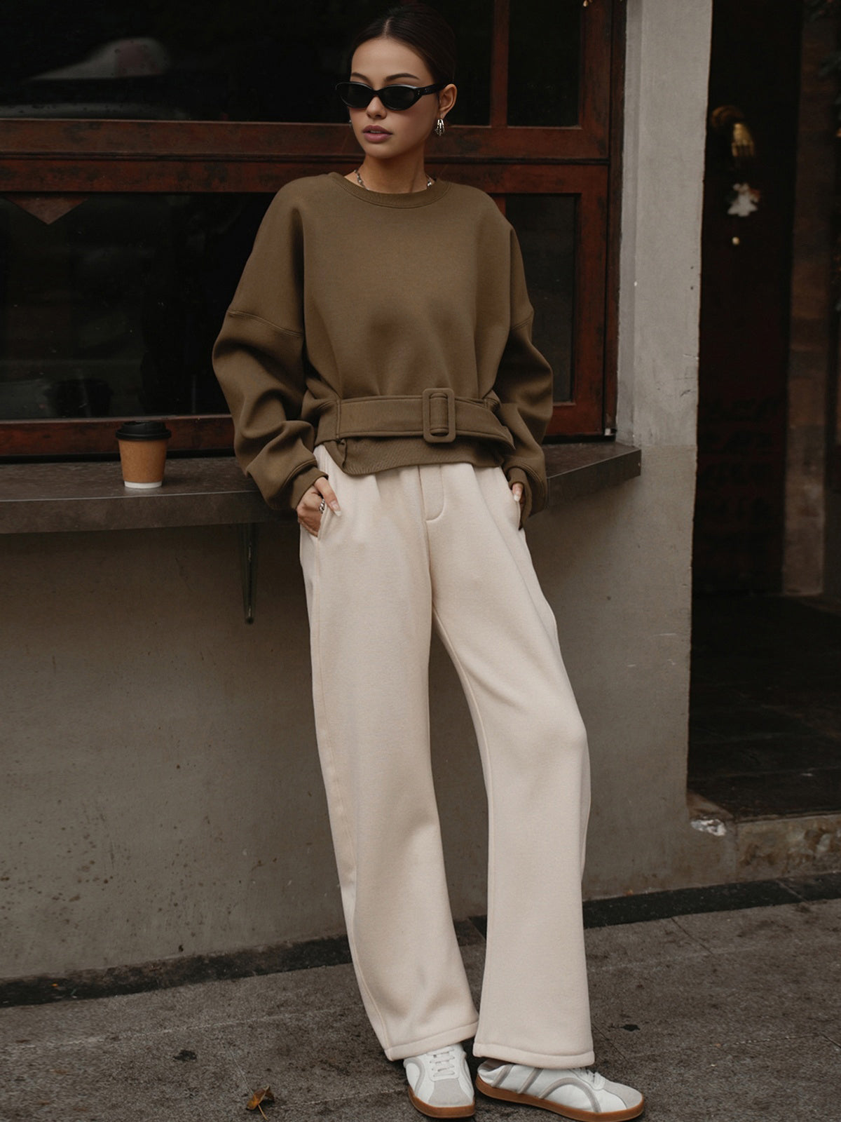 Cinched waist short sweatshirt sweater, cream wide-leg pants, and white sneakers.