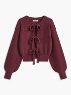 A cropped cardigan with lace trim, three bow ties, wide ribbed cuffs and hem.