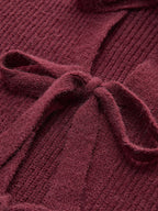Lace-trimmed tie-front cardigan, textured ribbed knit and bow detail, exuding feminine coziness.