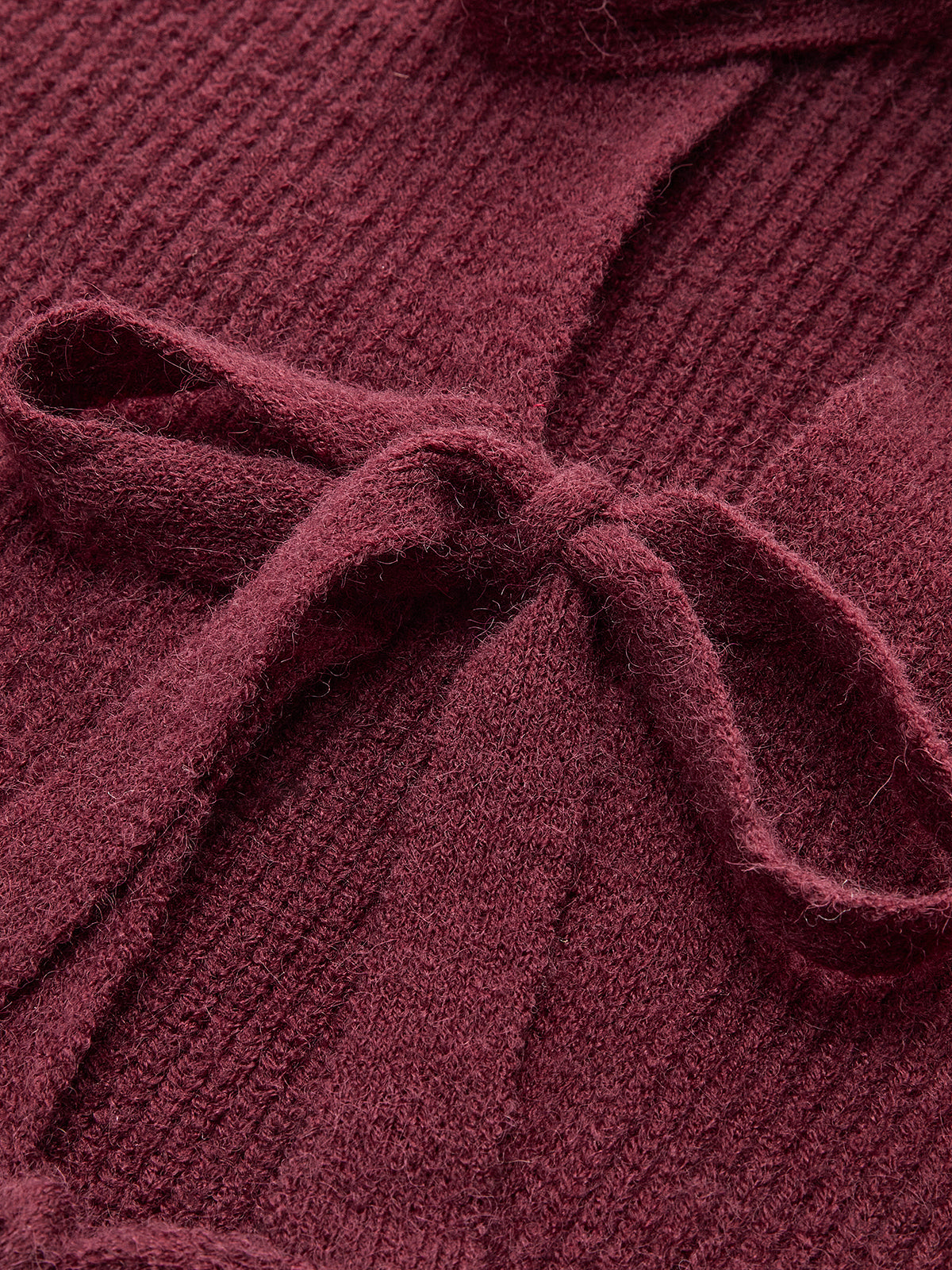 Lace-trimmed tie-front cardigan, textured ribbed knit and bow detail, exuding feminine coziness.