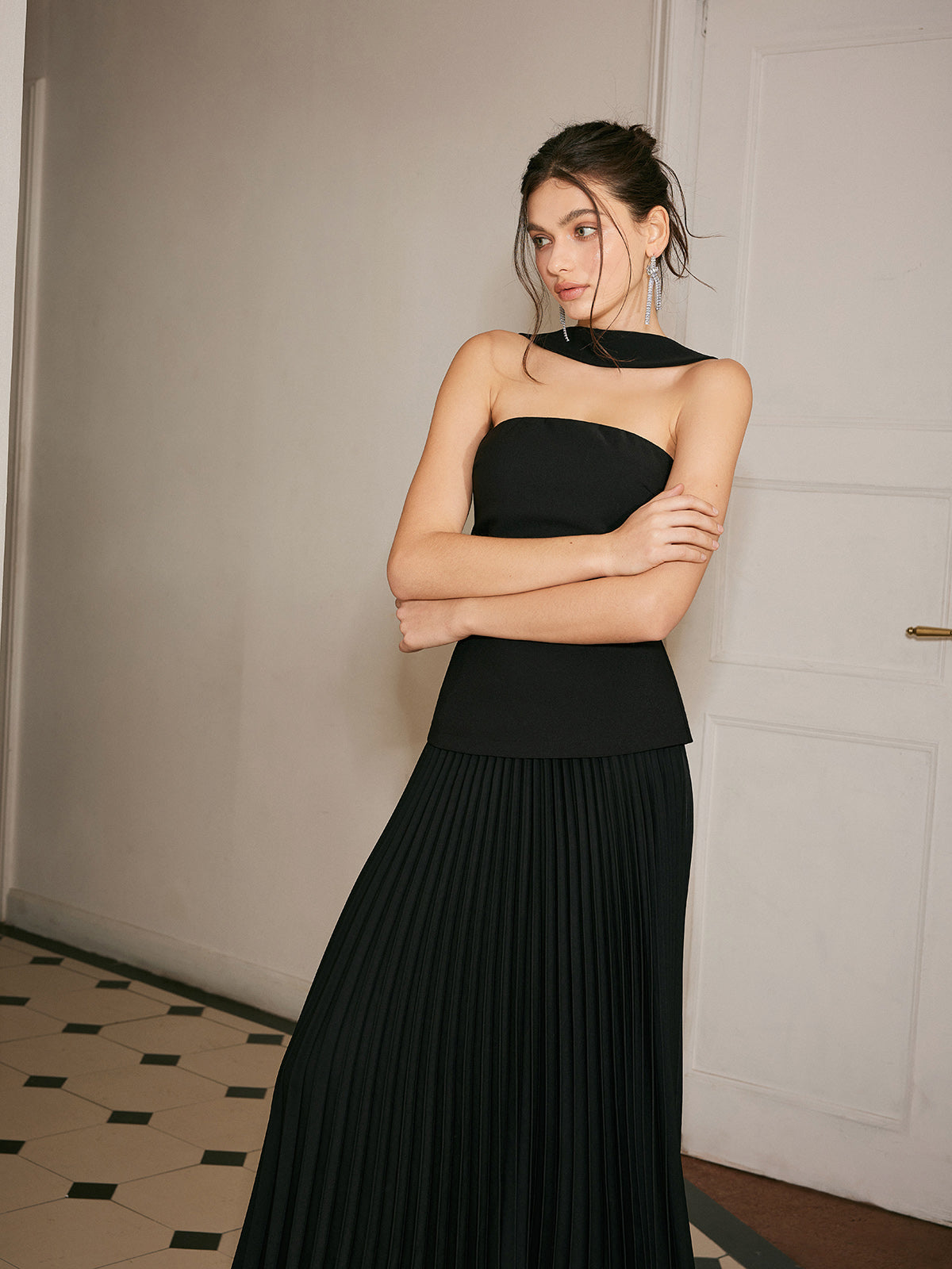 An elegant black sleeveless midi dress featuring a choker neck and pleated front detail.