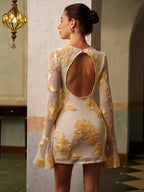 A slim-fit mesh dress with gold floral embroidery, long sleeves, and a dramatic backless design.