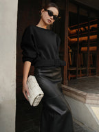 LA FINE FLEUR cinched waist short sweatshirt sweater paired with a black leather skirt.