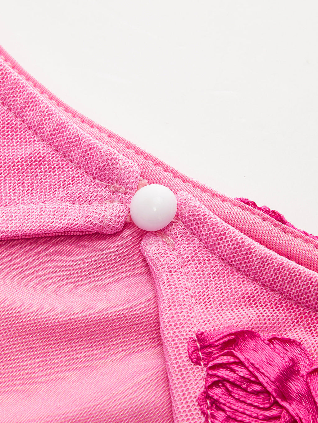 Elegant floral mesh dress with pink satin, embroidery, white button accent, and backless design.