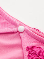 Elegant floral mesh dress with pink satin, embroidery, white button accent, and backless design.