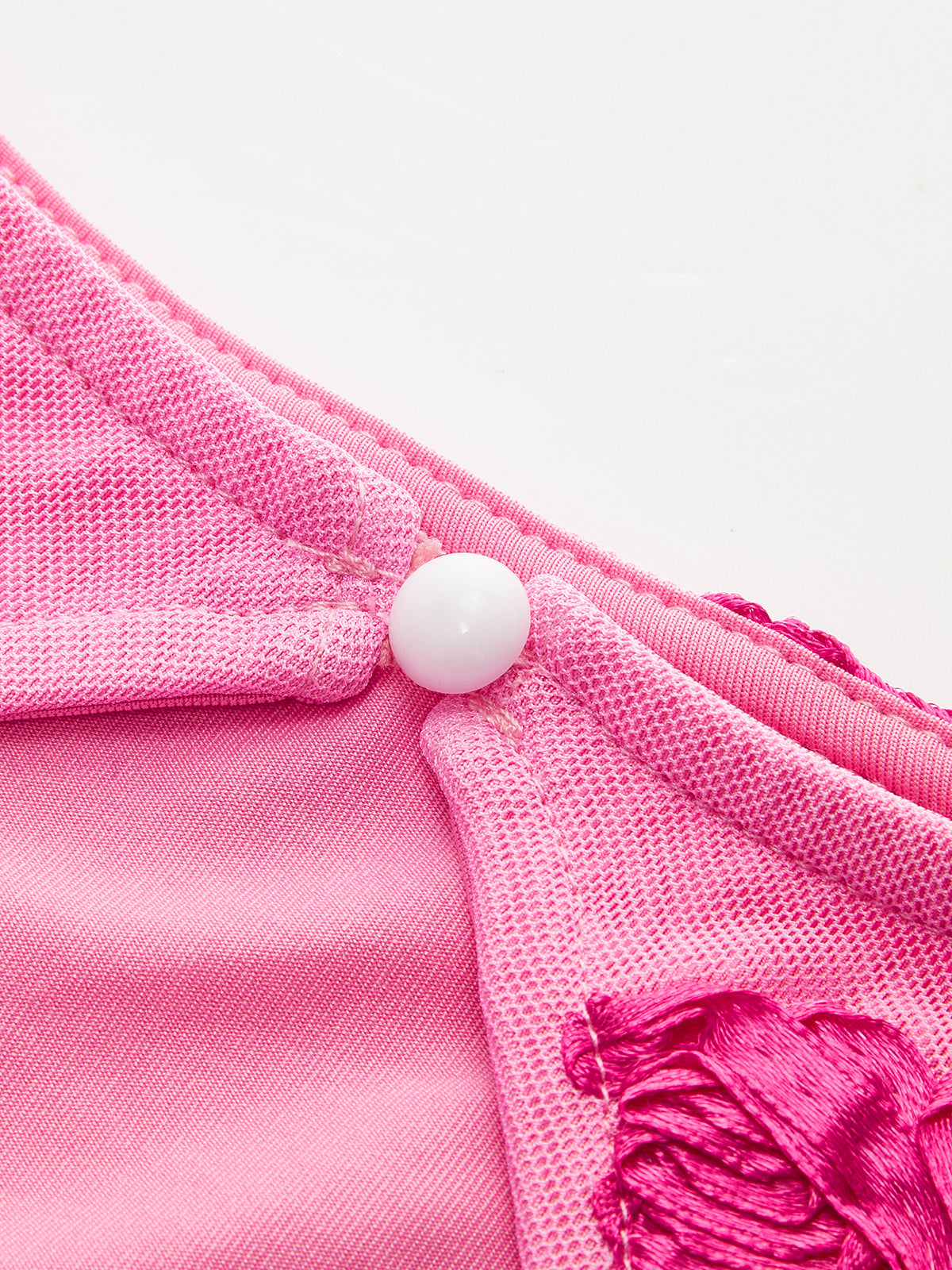 Elegant floral mesh dress with pink satin, embroidery, white button accent, and backless design.