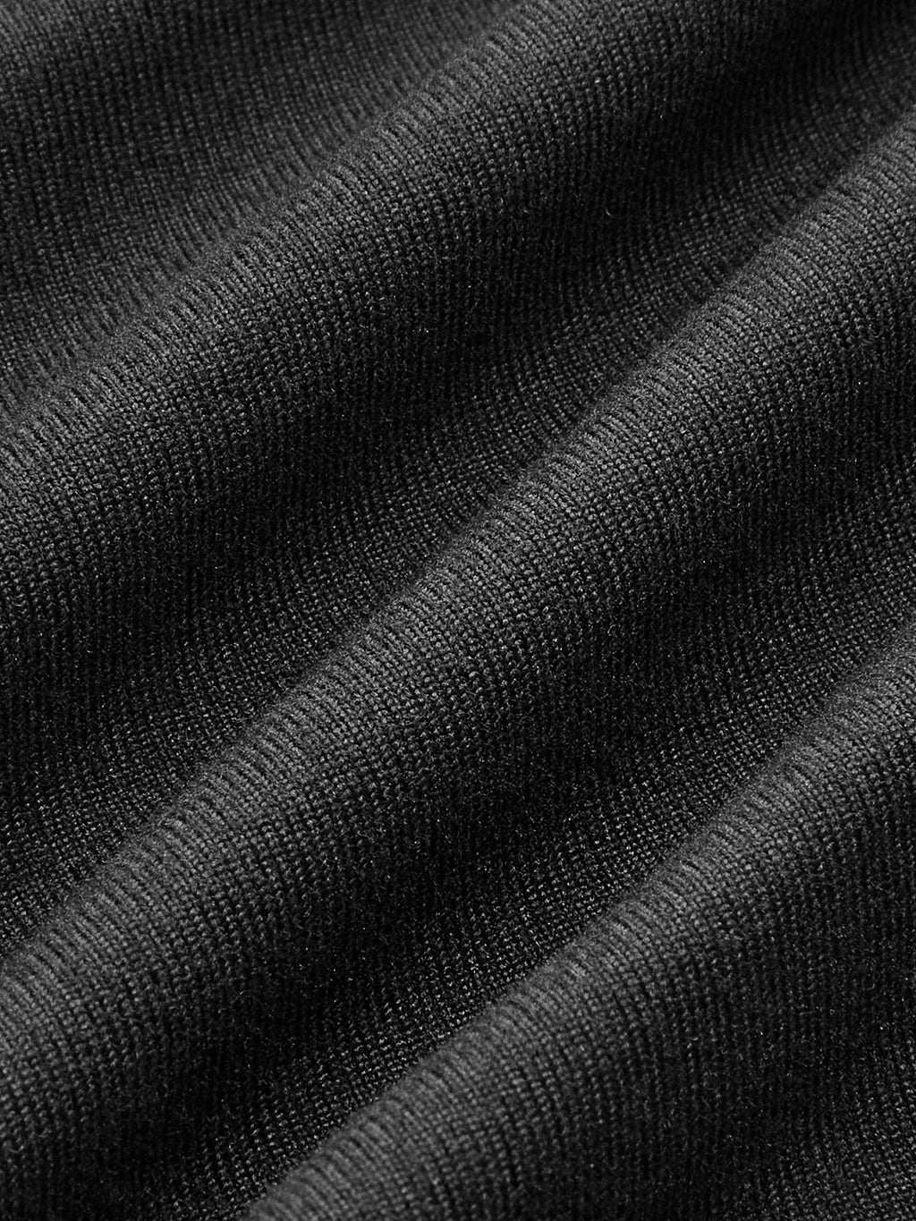 Close-up of black ribbed knit bodysuit fabric with visible texture and diagonal folds.