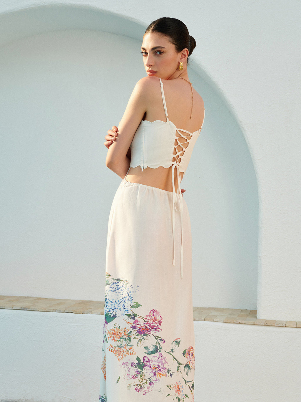Sleeveless floral lace-up dress with adjustable straps and delicate floral accents at the hem.