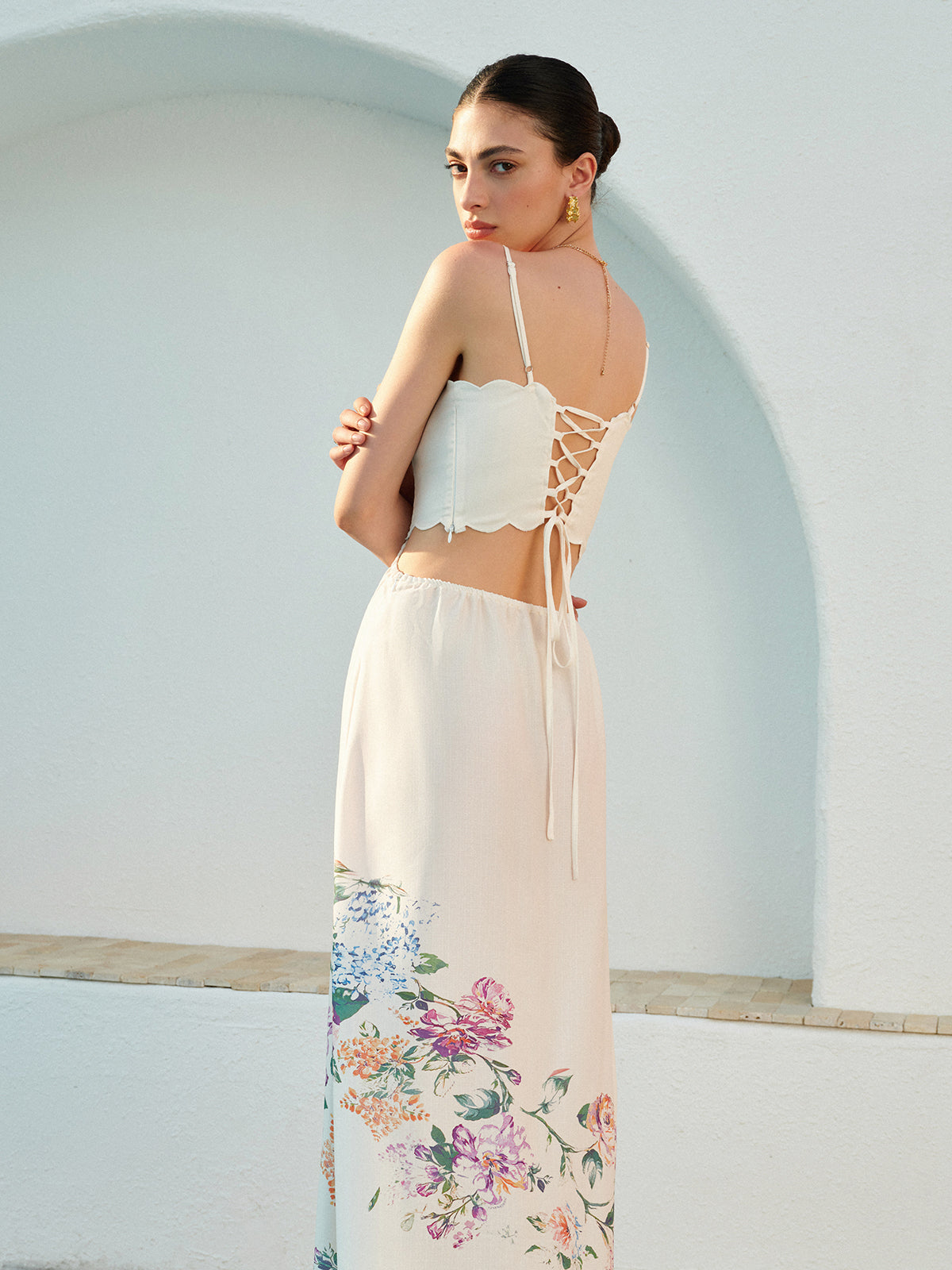 Sleeveless floral lace-up dress with adjustable straps and delicate floral accents at the hem.