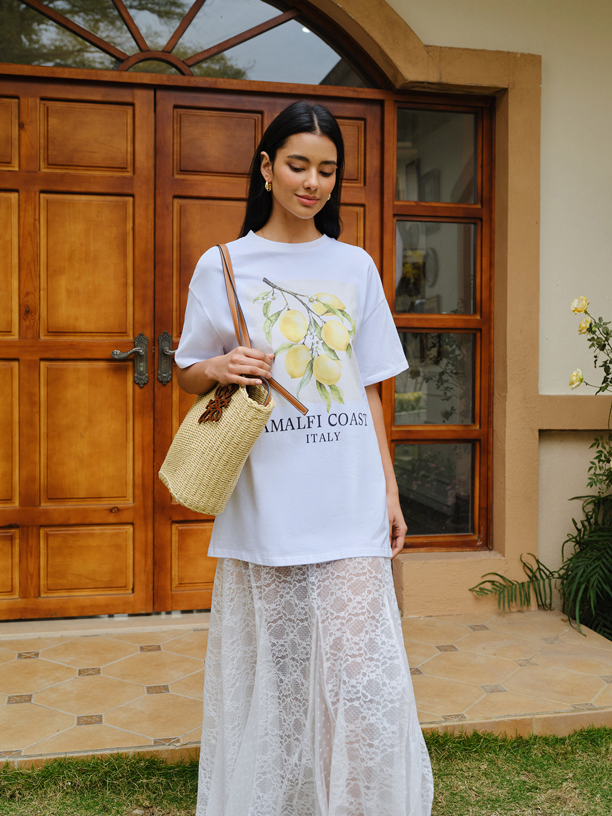 Oversized LA FINE FLEUR cotton print tee with lemon graphic and "AMALFI COAST ITALY" text, long white lace skirt.