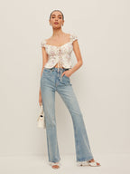 Tie-front bustier top with ruffled sleeves paired with light blue high-waisted jeans.
