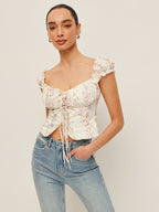 LA FINE FLEUR Tie-Front Bustier Top with Ruffled Sleeves paired with light blue jeans.