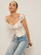 A tie-front bustier top with ruffled sleeves paired with light blue jeans.