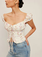LA FINE FLEUR Tie-Front Bustier Top with ruffled sleeves and cropped fit, light wash jeans.