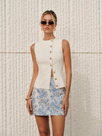 Asymmetric closure textured knit vest over a cream ribbed top and blue floral jacquard mini skirt.