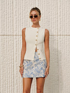 LA FINE FLEUR's Asymmetric Closure Textured Knit Vest with gold buttons and a blue floral skirt.
