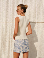 White sleeveless top, LA FINE FLEUR’s Asymmetric Closure Textured Knit Vest, blue-and-white floral skirt.