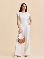 LA FINE FLEUR Cap Sleeve Jumpsuit with Buttoned Backless Design and white sandals.