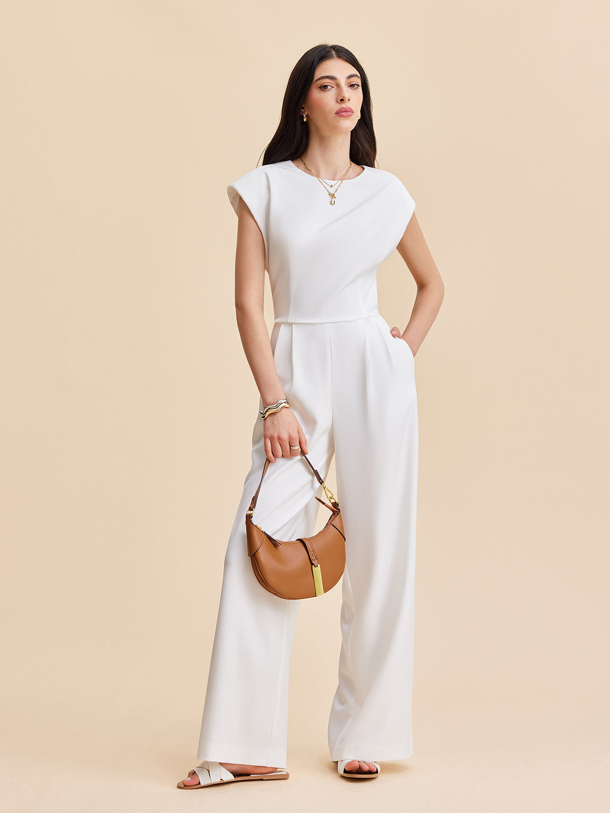 LA FINE FLEUR Cap Sleeve Jumpsuit with Buttoned Backless Design and white sandals.