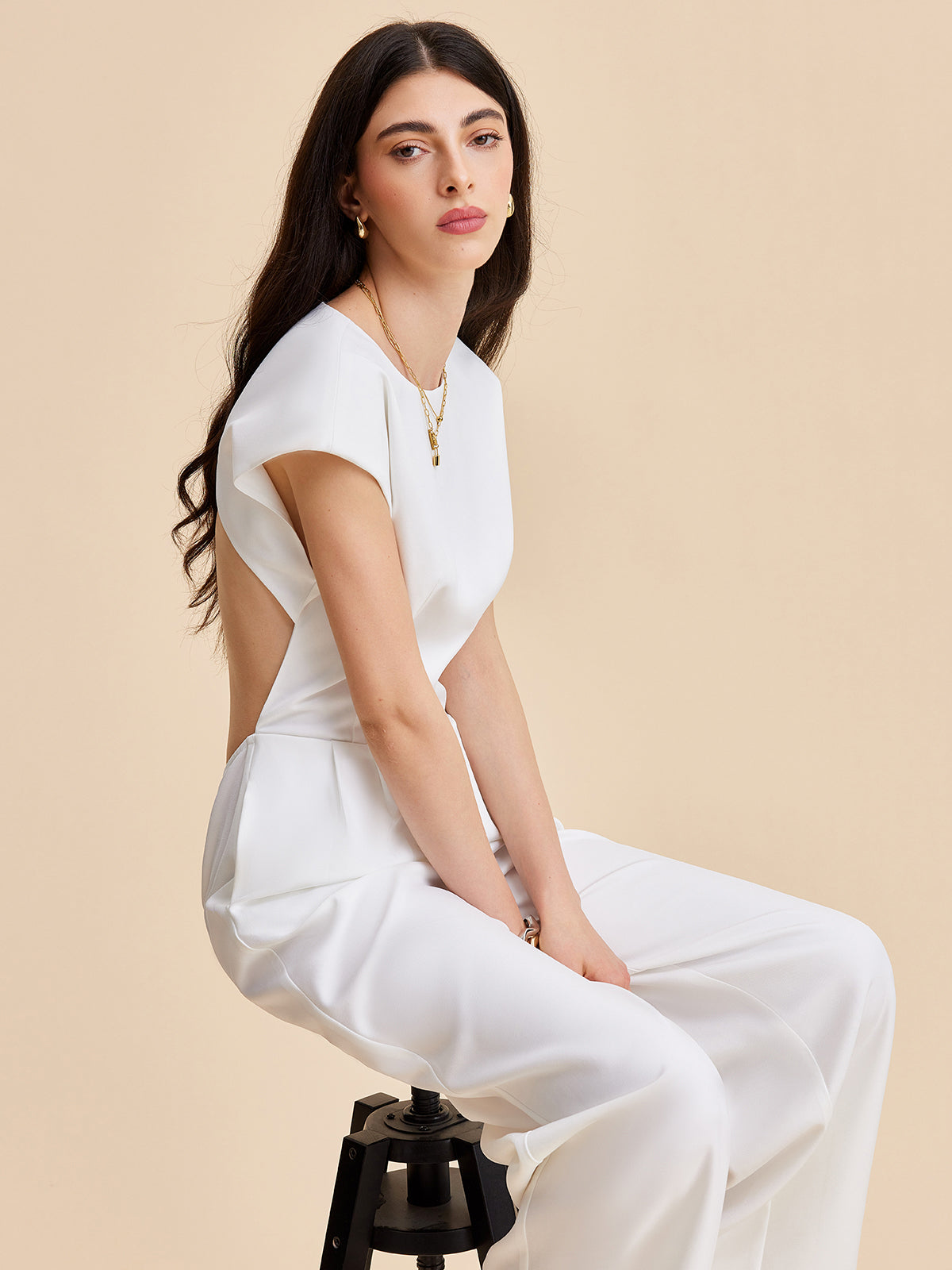 A cap sleeve jumpsuit with a buttoned backless design in a minimalist, modern style.