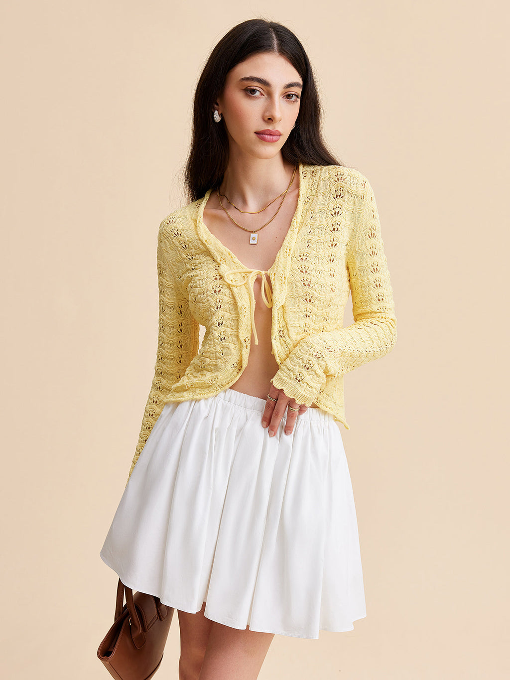 The LA FINE FLEUR crocheted cardigan sweater with a tie-front design and a white skirt.