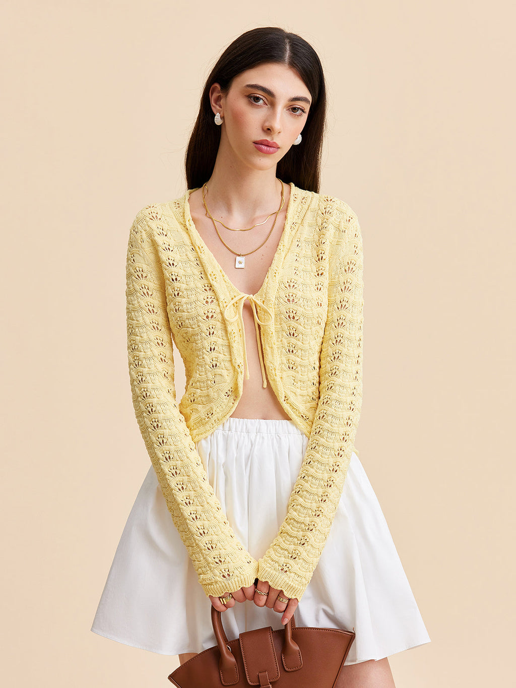 LA FINE FLEUR Crocheted Cardigan Sweater with Tie-Front Design over a white top and skirt.