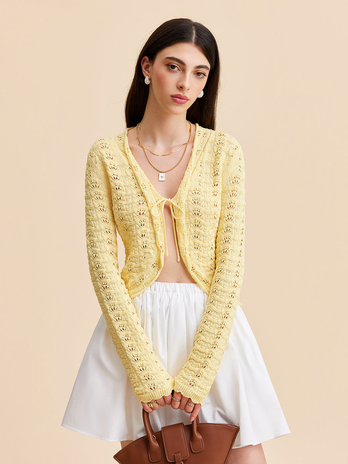 LA FINE FLEUR Crocheted Cardigan Sweater with Tie-Front Design over a white top and skirt.