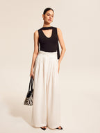 V-neck blouse with elegant scarf-style neck tie paired with wide-leg white pants.